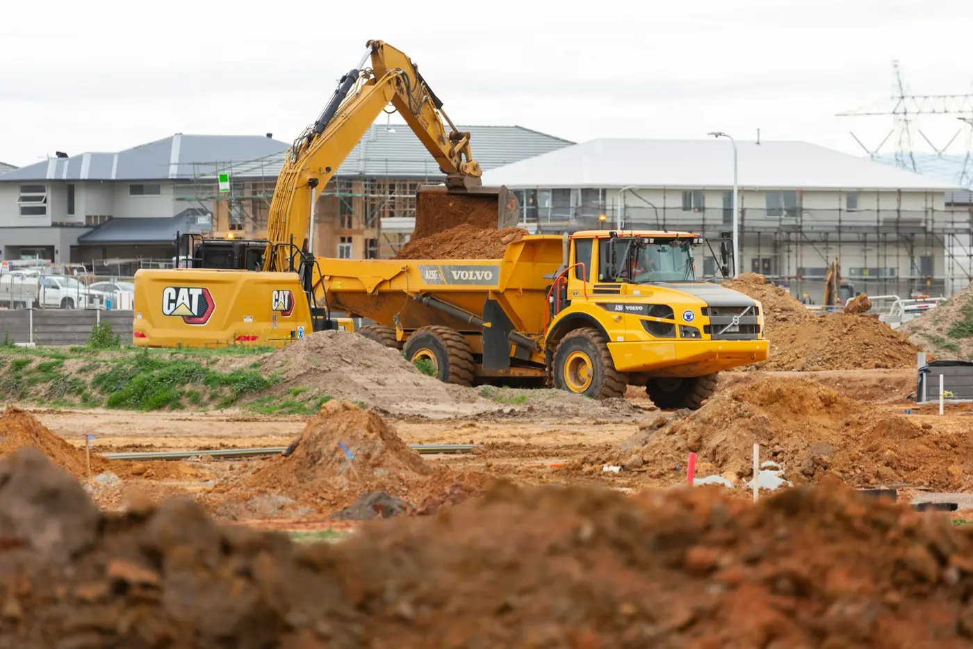 A Cat excavator loading a Volvo articulated hauler on a construction site