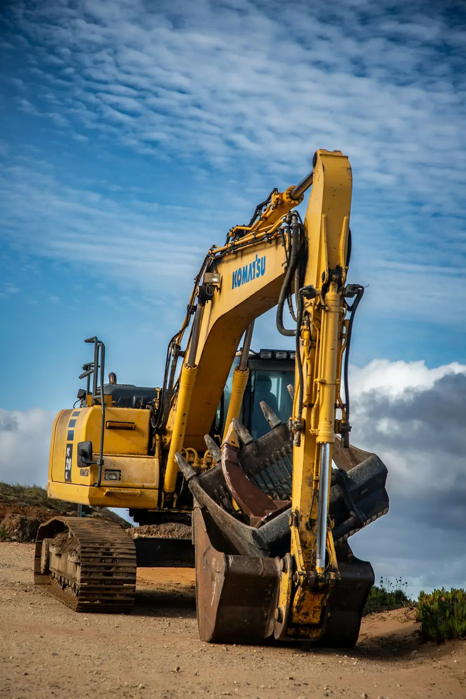 A yellow Komatsu excavator against a blue sky