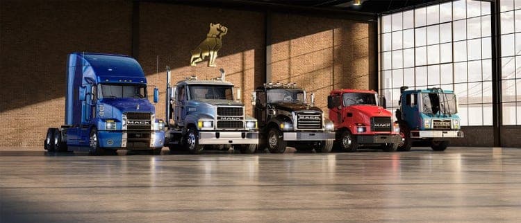 Multiple Mack trucks parked in an outlet.