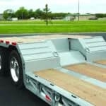 Wheel area featuring a deep mini-boom trough for hitch clearance, removable step plates for axle access, and standard traction aids with D-rings for secure heavy-haul transitions